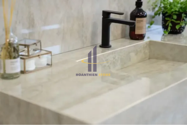 Bàn đá lavabo tông be sáng nguyên khối, thiết kế liền chậu, bề mặt mịn cùng vân đá nhẹ nhàng, mang lại cảm giác hiện đại và tinh tế cho phòng tắm.