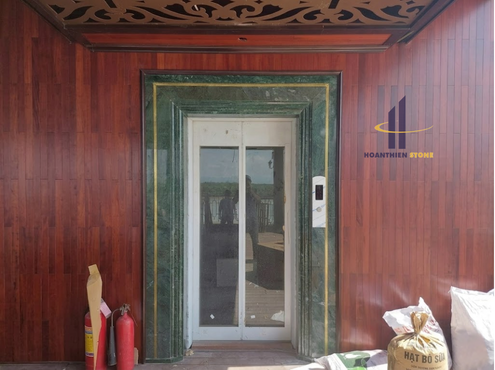 Mặt thang máy được ốp đá xanh tự nhiên kết hợp đường chỉ vàng tinh tế, thể hiện kỹ thuật gia công và thi công đá cao cấp của HOANTHIEN STONE.